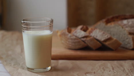 vaso de leche y pan en rodajas en la mesa de la cocina. producto lácteo en el desayuno