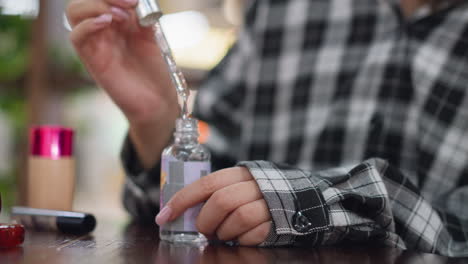 closeup view of young lady carefully opening a face serum bottle using a dropper, her manicured hands gently handle the skincare product, surrounded by beauty essentials on a wooden table