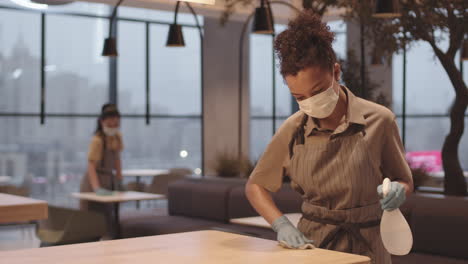 female cafe worker disinfecting table