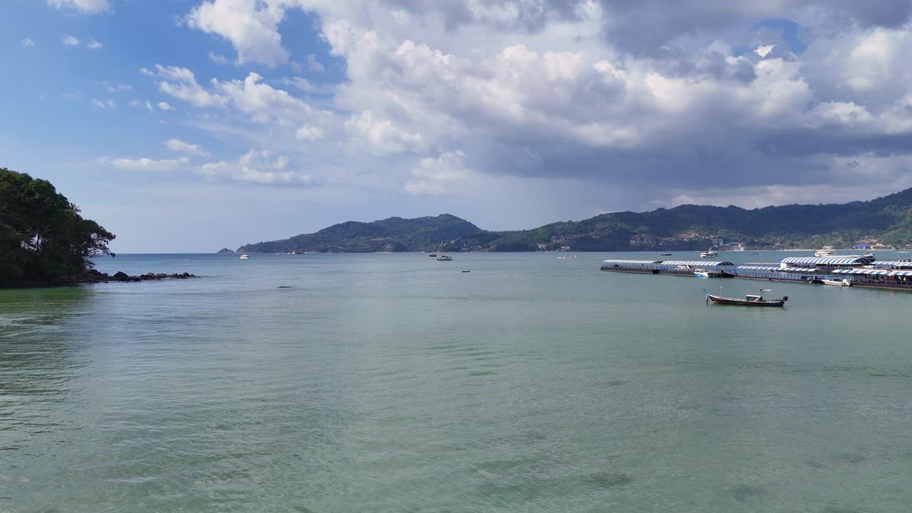 Aerial footage captures longtail boats and pontoons on Phuket's calm waters, showcasing stunning landscapes and vibrant skies