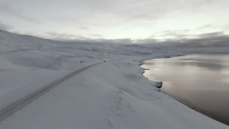 car driving on frozen snowy road on ocean shore, dolly forward shot