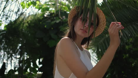 woman in straw hat, hidden by palm leaves