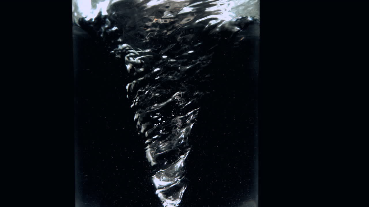 Whirlpool in glass of water on black background