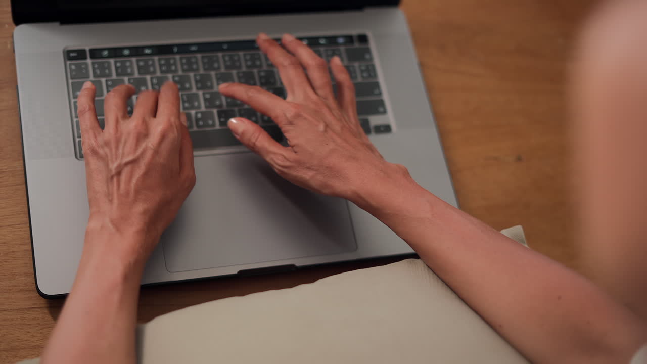 Thin woman hands typing on laptop keyboard view from behind