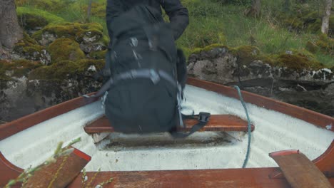 Young-man-puts-backpack-onto-boat-bow-and-climbs-in