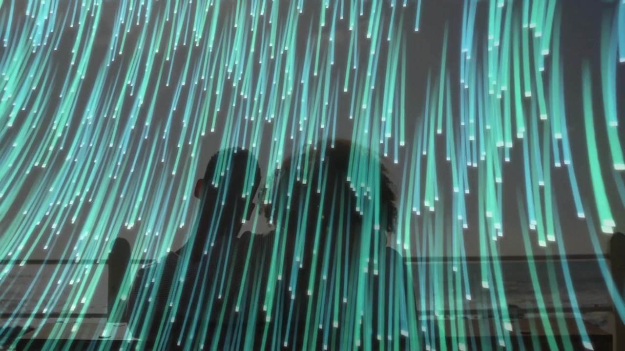 Silhouettes of a Couple Watching Glowing Blue and Green Digital Lines
