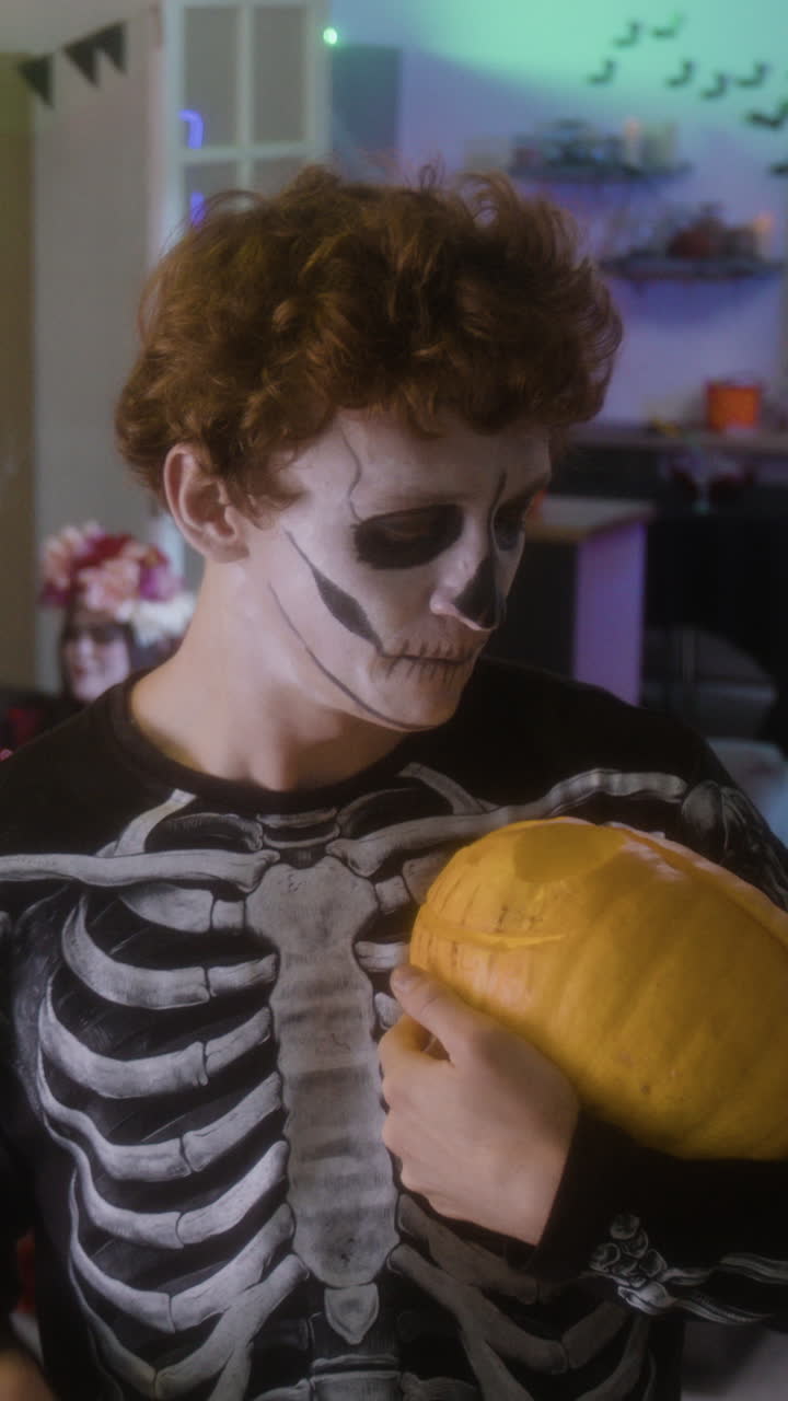 Teenager in Skeleton Costume with Pumpkin for Halloween