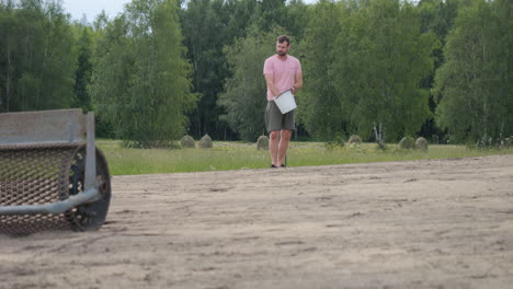 young man sowing grass in his garden at daytime