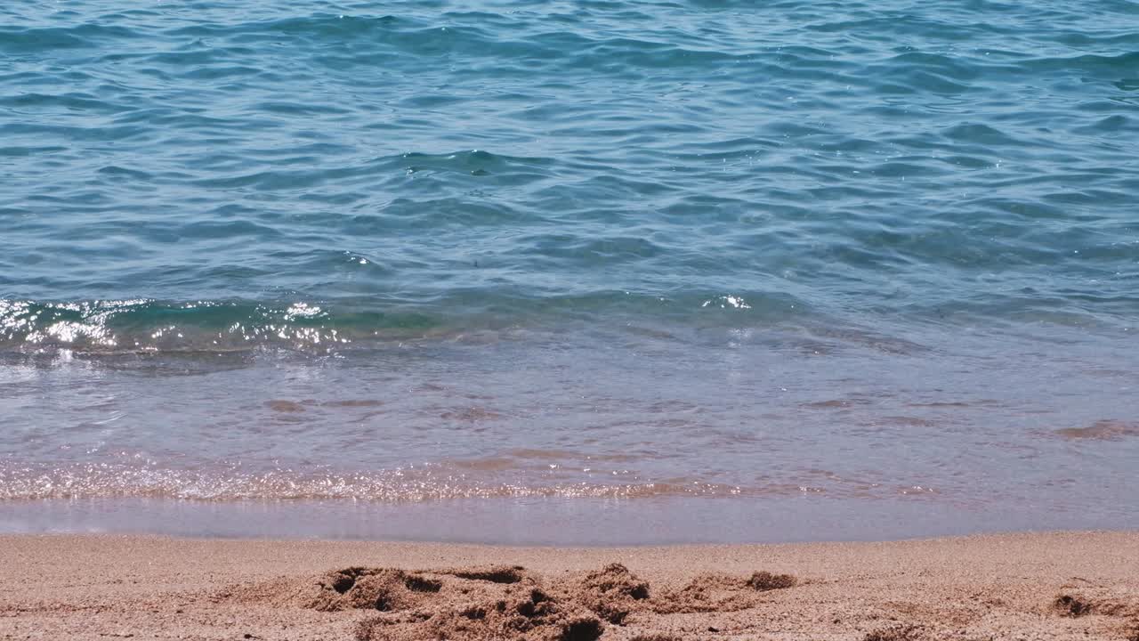 Close-up shot of the waves and the sand at the coastline in the morning in Cannes, France