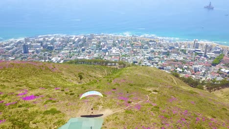 Drohnenantenne-über-Gleitschirmfliegen-Und-Gleitschirmflieger-Mit-Der-Innenstadt-Von-Kapstadt-Südafrika-Im-Hintergrund-2