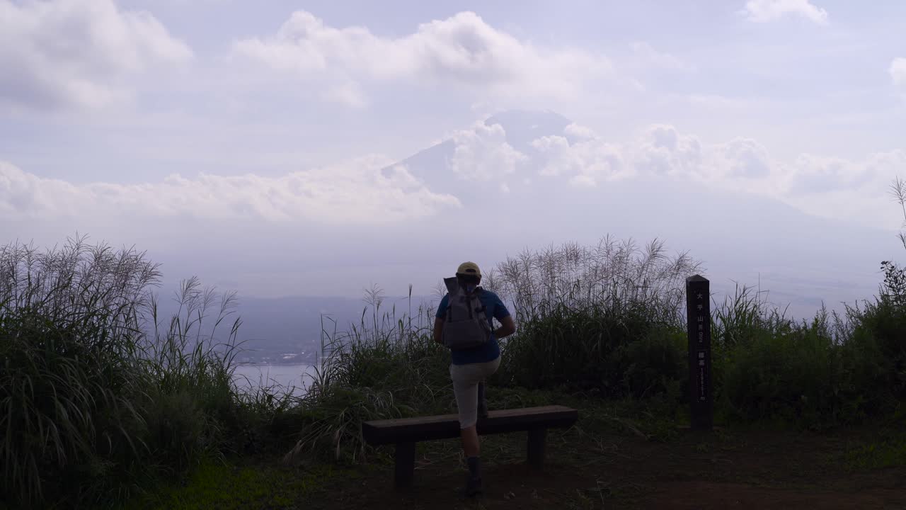 excursionista masculino escalando en la parte superior del banco cerca del monte fuji mirando a la distancia