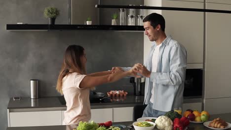Happy-young-couple-dancing-in-kitchen.-Caucasian-family-in-casual-clothes-having-fun-dance-together,-enjoying-happy-morning,-romantic-relationship-at-home.-Slow-motion