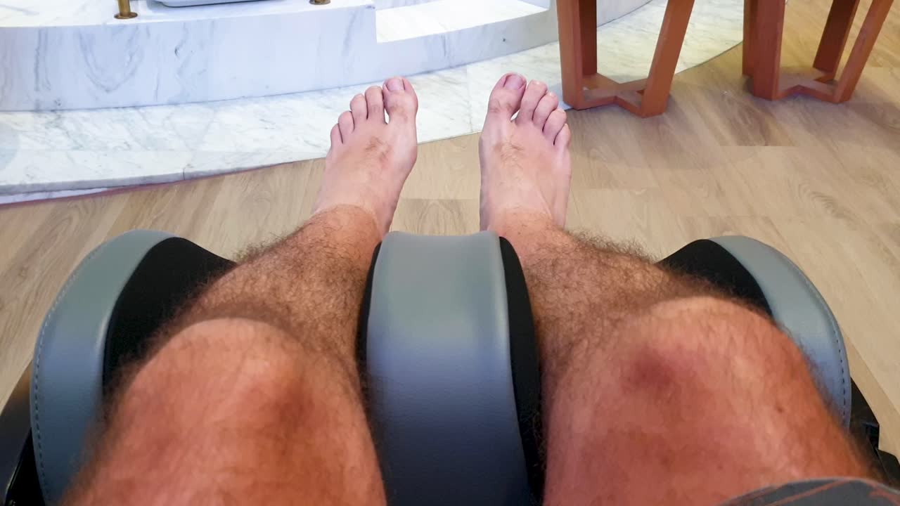 First person view of automatic massage chair massaging persons legs and calf muscles, self care and pampering at health and beauty spa salon