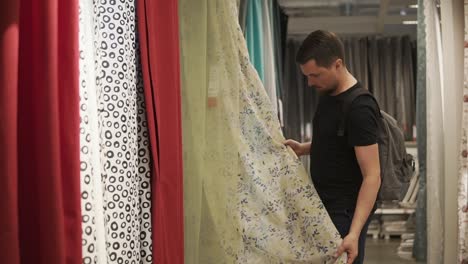 man choosing curtains in a fabric store