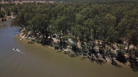 Drone-aerial-going-up-speed-boat-over-muddy-river