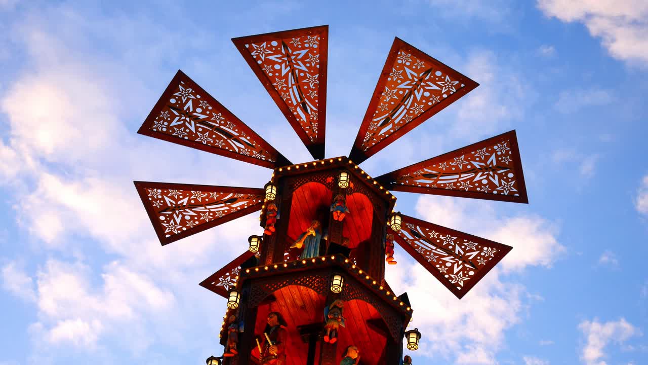 molino de viento de carrusel giratorio iluminado festivo del mercado de navidad contra el cielo azul que pasa las nubes