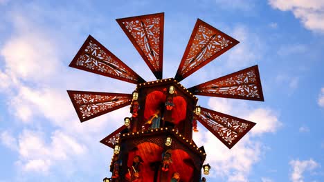 christmas market festive illuminated rotating carousel windmill against blue sky passing clouds