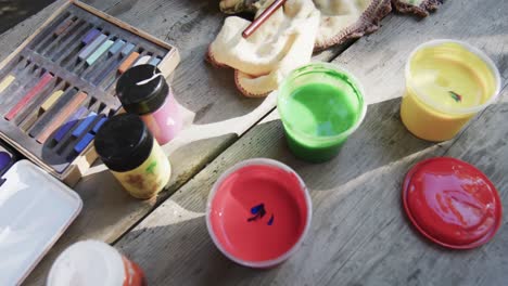 close up of paints and brushes on table in sunny garden, slow motion