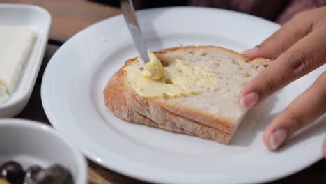 person spreading butter on a slice of bread