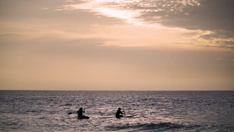Zwei-Junge-Frauen-Stehen-Auf-Ihren-SUPs-Beim-Stand-up-Paddle-Boarding-In-Hawaii-Bei-Sonnenuntergang-–-Malerischer,-Farbenfroher-Sonnenuntergang-über-Dem-Meer