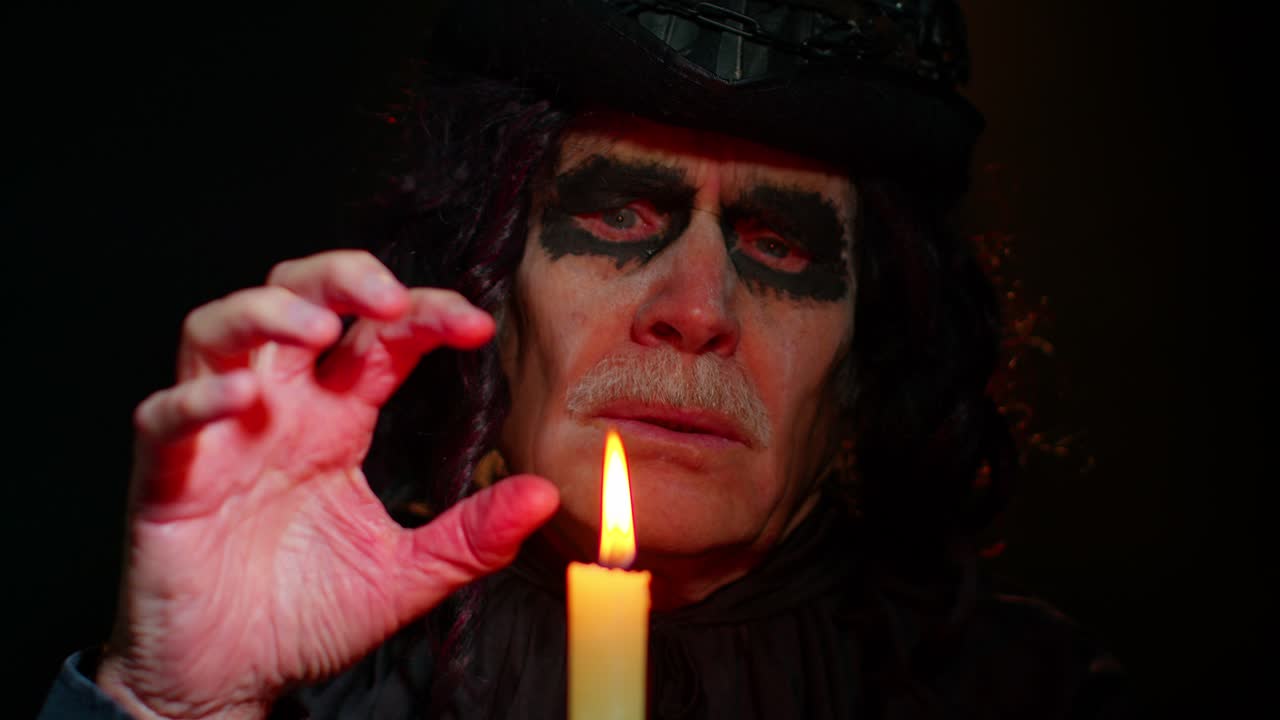 Creepy mature man grandfather with Halloween stylish witcher makeup making voodoo magic rituals