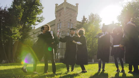 multi ethical happy graduates hugging and congratulating each other cheerfully in their graduation day in front of the university