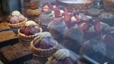 a bakery display case with various pastries, including those with strawberries, whipped cream, and chocolate