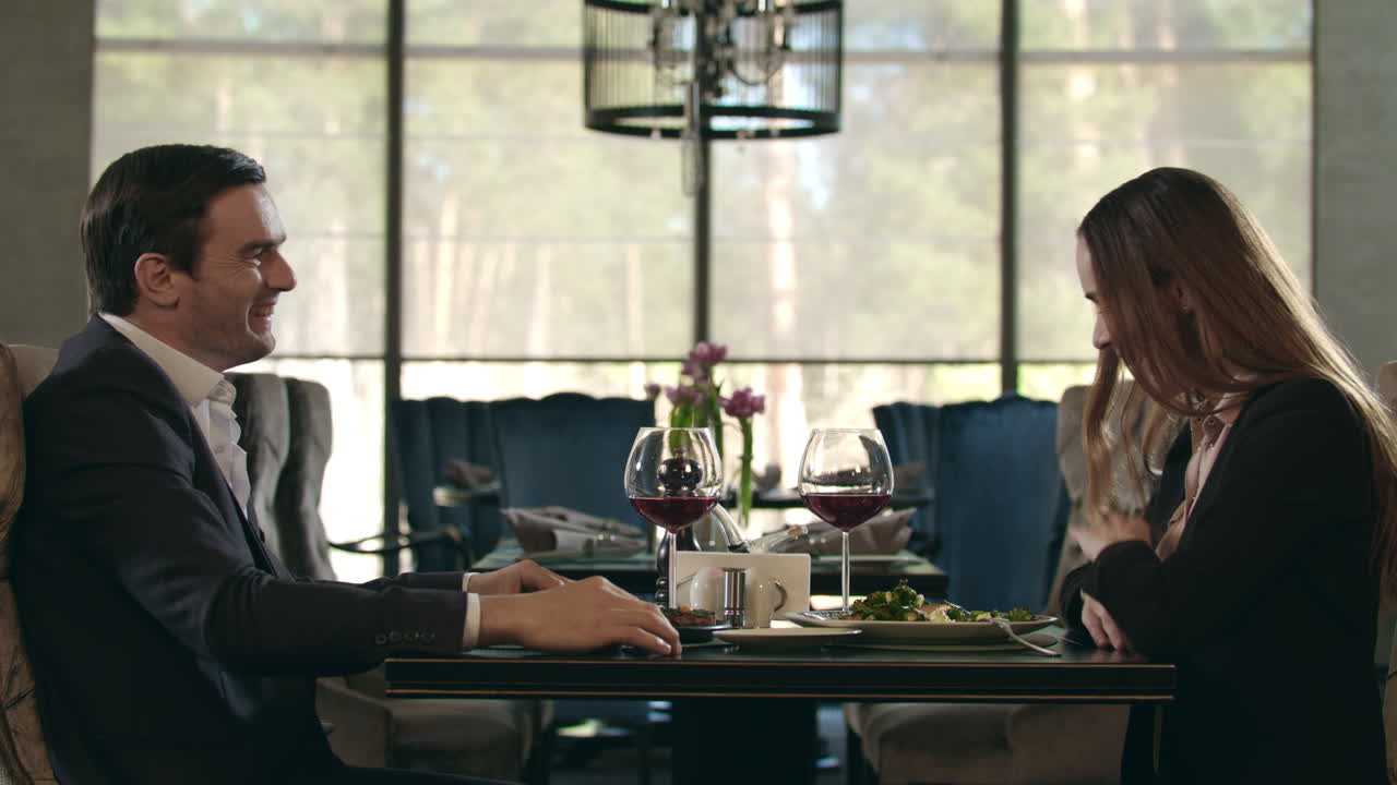 행복한 커플이 레스토랑에서 손 다섯을 주고 있습니다. 남자와 여자가 와인 잔을  ⁇ 습니다.