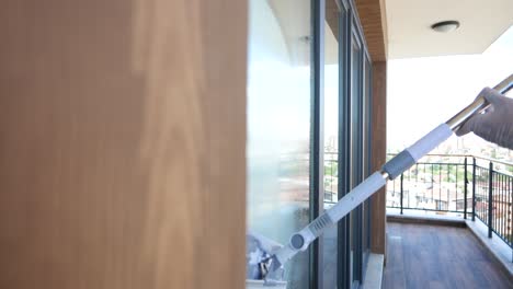 a woman cleans a window on a balcony overlooking a city