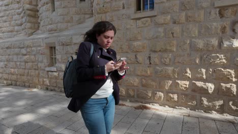 young tourist walking and using smartphone in jerusalem old city. slow motion.