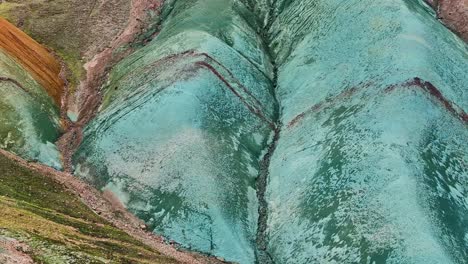 aerial drone frontal, very close shot sliding down the face of grænihryggur, the green rock, in landmannalaugar, iceland, emphasizing the medium tones of orange and green