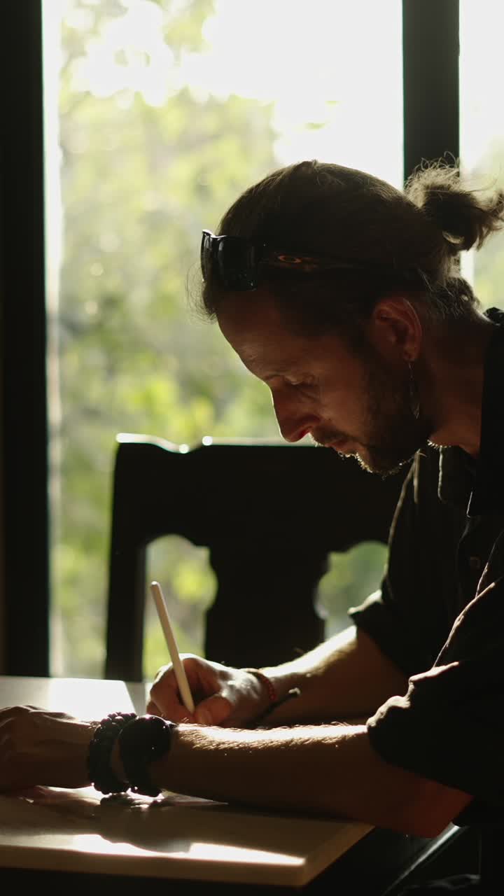 Man drawing by the window