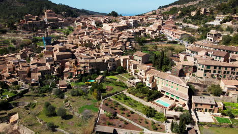 Breathtaking-aerial-reveal-of-Deia-will-coastline-and-mountains-in-view-on-hot-Spanish-summer-day