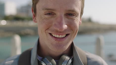 retrato de cerca de un joven alegre sonriendo feliz en una playa soleada