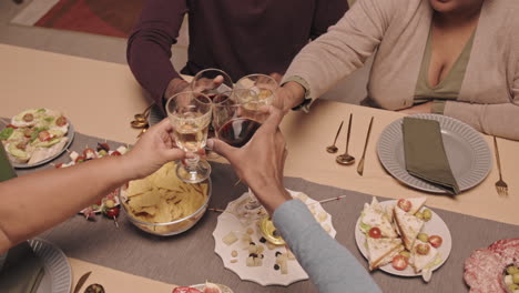 family and friends gather for a dinner party and toast with wine glasses