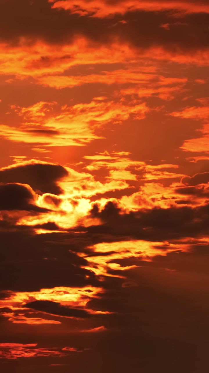 Lebhafter orange-roter Himmel mit Sonne, die durch die Wolken lugt