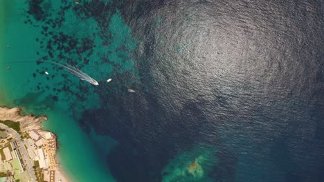 il motoscafo naviga nell'acqua di mare blu turchese vicino alla costa rocciosa e al luogo di villeggiatura in albania