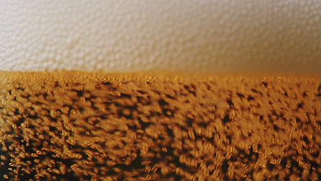 Macro-shot-of-pouring-beer-with-bubbles-and-foam-into-a-glass