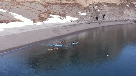 kayakistas saliendo de la playa en el fiordo de islandia con aguas tranquilas y claras, holmanes