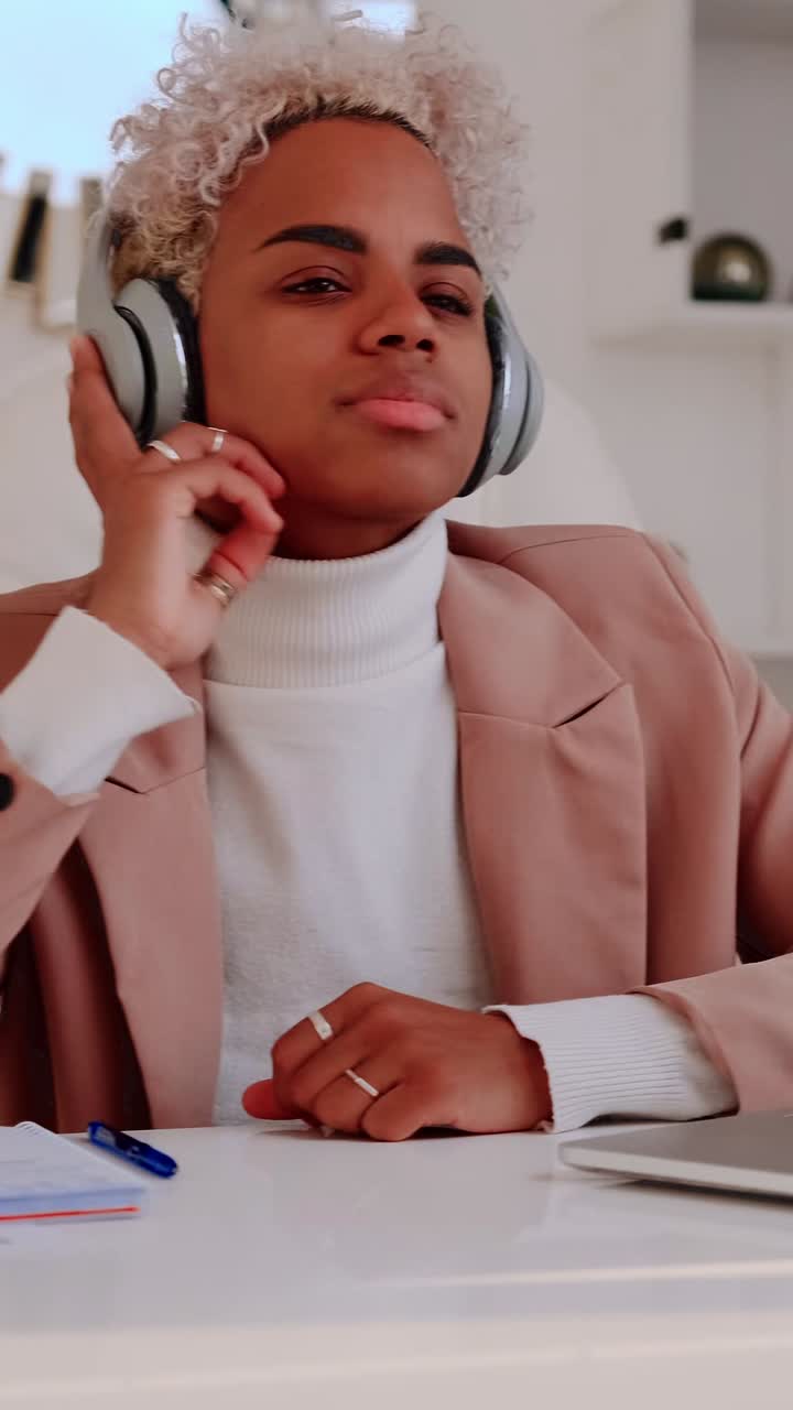 Young adult with headphones closes eyes and enjoys music while seated at desk