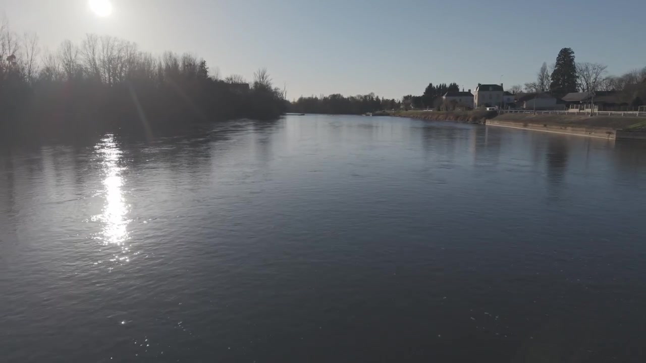 Et luftfoto fanger skarpt sollys, der reflekteres fra Loire-flodens rolige overflade i Frankrig