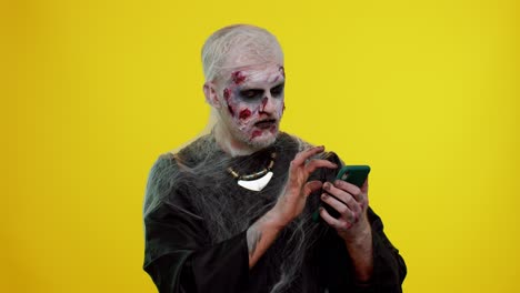 feliz emocionado hombre siniestro halloween zombi uso de teléfono inteligente celebrando la lotería ganar, éxito suerte