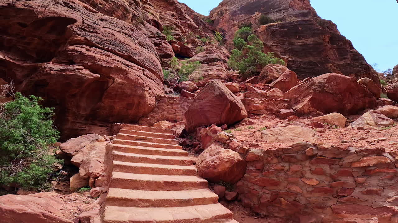 Stone stairs at the foot of the high rocks. Scarce trees grow on the sandstones. Low angle view on the famous Petra, Jordan, West Asia.
