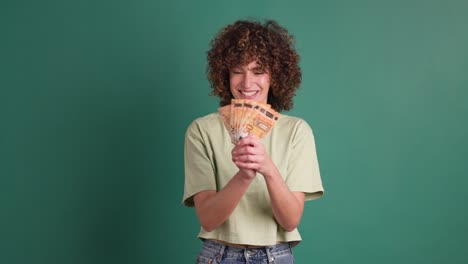 cheerful woman showing euro banknotes in green studio