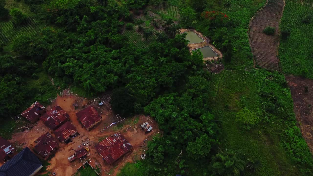 Aerial of small remote town surrounded by green marshes and farmland in rural Nigeria, Africa