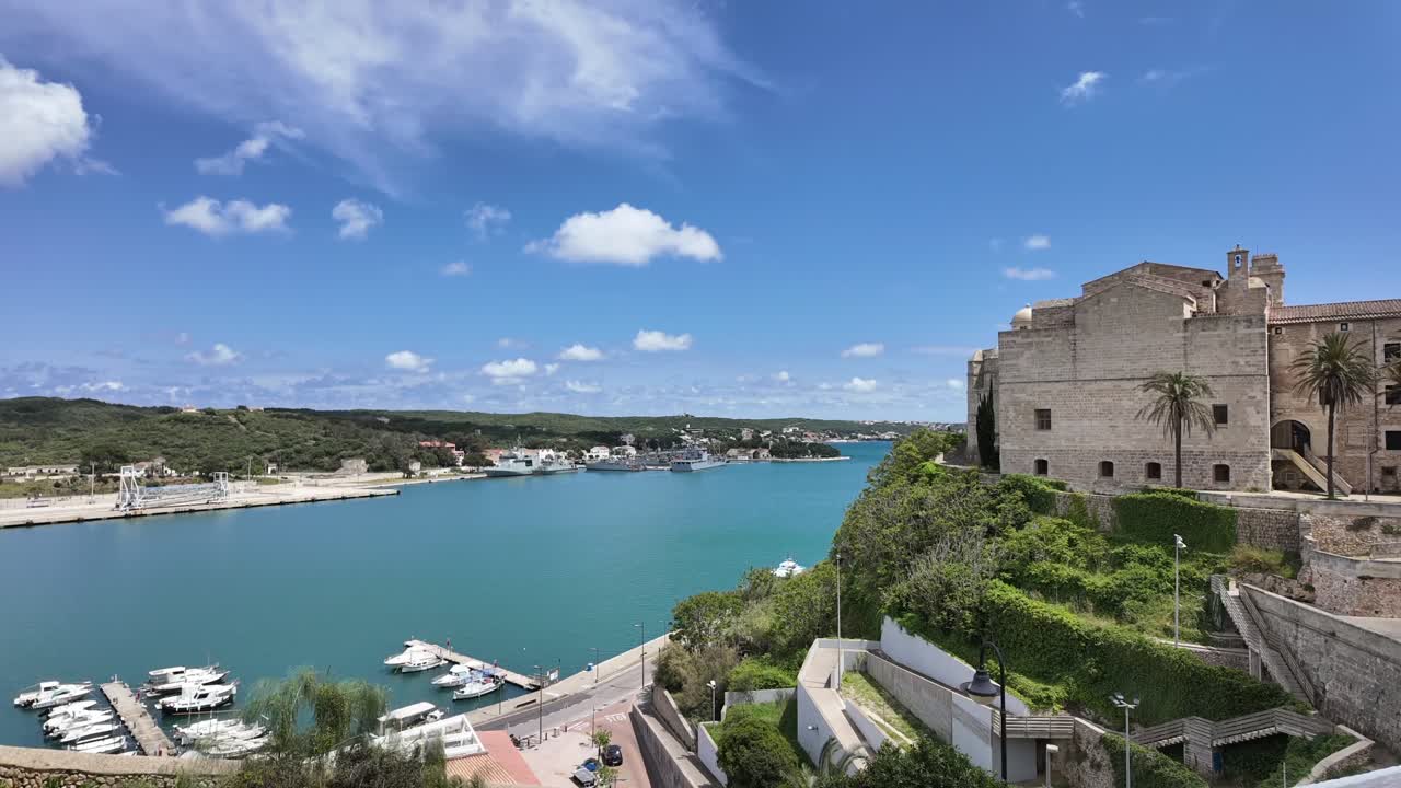 A time lapse from an elevated point of view of the bay of Mahon island, with some clouds in a blue sky and its shadows on a wavy sea