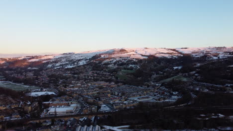 Toma-De-Drones-Del-Sol-De-Invierno-Brillando-En-Las-Colinas-Nevadas-De-Una-Pequeña-Ciudad-De-Yorkshire