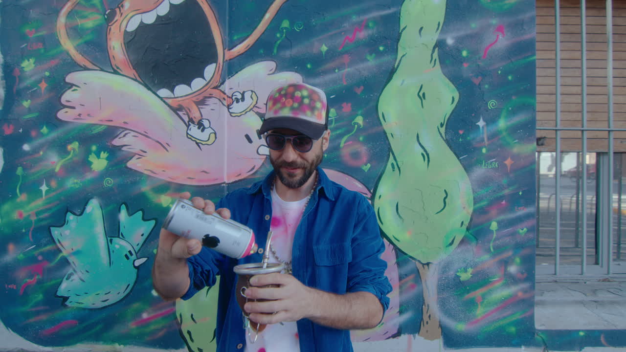 Artista di graffiti in posa per la fotocamera con una bevanda per strada