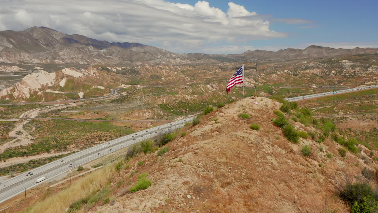 American flag on top of a hill near highway 15 near Phelan, California. Aerial shot