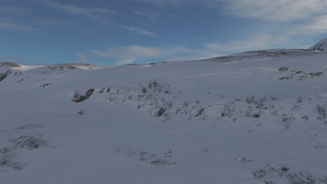 forwards flying wide landscape droneshot flying near frozen snowy mountains in norway on a bright day log